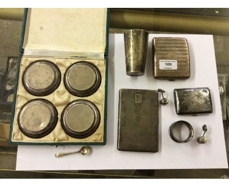 Three silver cigarette cases; a continental silver beaker; a silver serviette ring; a set of four white metal dishes etc.