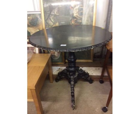 A carved wooden ebonised tripod table