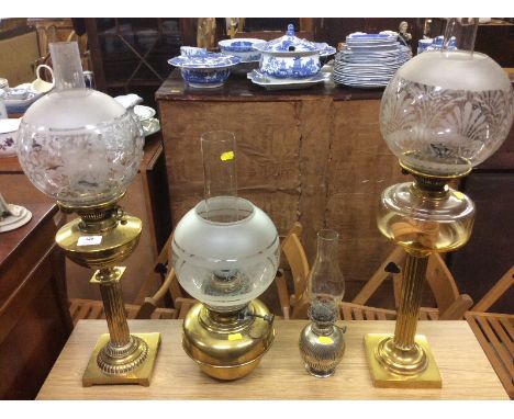 Two brass Corinthian column oil lamps; a silver plated oil lamp and one other