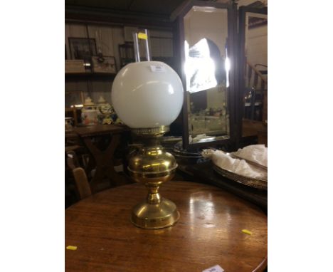 A brass oil lamp with milk glass shade