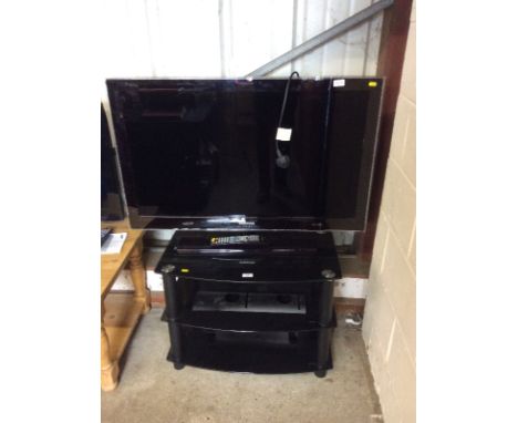 A Samsung flat screen television with remote control and glass three tier television stand