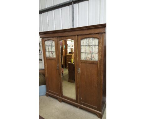 An Art Nouveau oak and leaded glazed triple wardrobe by Shapland & Petter