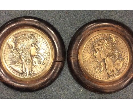 A pair of Art Nouveau circular brass plaques in oak frames. Approx. 30 cms in diameter each. Est. £80 - £120.
