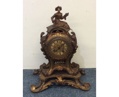 A French brass mantle clock decorated with scrolls and flowers with figure to top. Est. £80 - £120.
