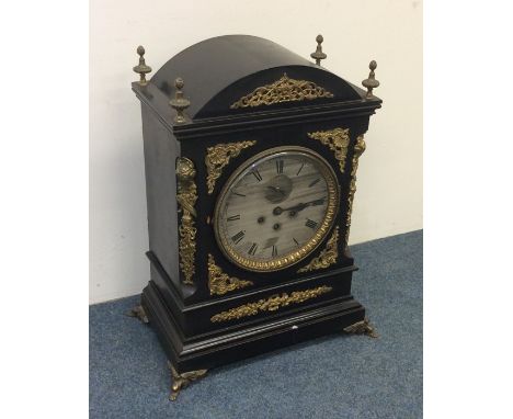 A massive bracket clock attractively decorated with scrolls and brass work with silvered dial and striking movement entitled,