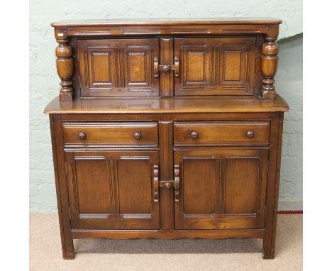 An Ercol dark oak court cupboard with turned pilaster supports.