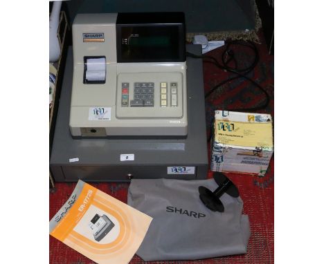 A Sharp electric cash register with cover box of till rolls and manual.