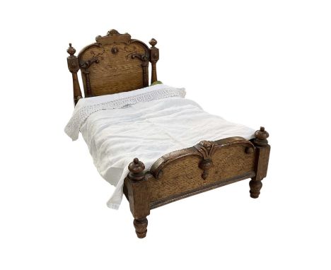 An early 20th century oak doll's bed, with carved decoration, on turned supports, length approx 60cm, width approx 32cm.