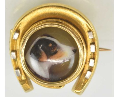 A yellow metal horseshoe brooch, the centre set with hand painted ceramic miniature depicting a dog, 1.8 x 1.8cm, approx 3.9g