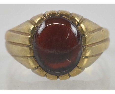 A 9ct gold signet ring with an oval set red cabochon stone, in line patterned mount and shoulders, size R, approx 5.2g.