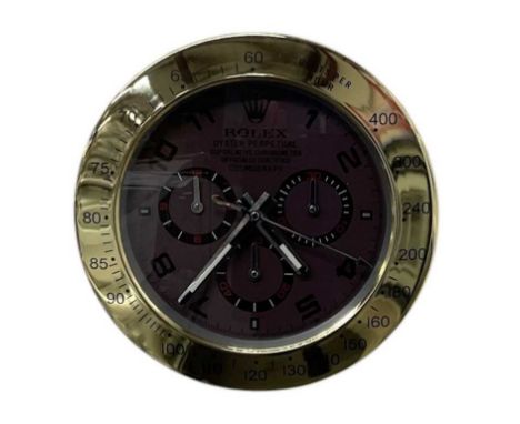 A decorative Rolex Daytona style dealer's wall clock, the brown dial set with subsidiary seconds and inscribed 'Daytona', wit