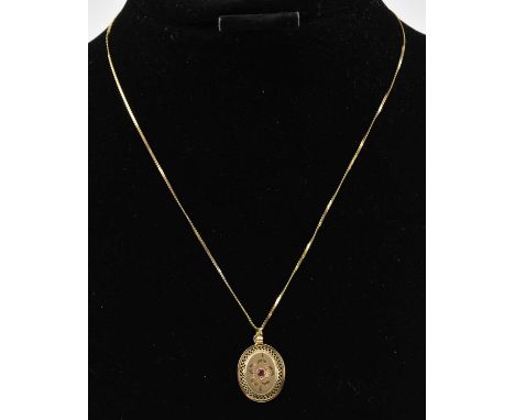 A 9ct gold oval necklace pendant set with central tiny ruby, on a 9ct gold thin dainty necklace, length 40cm, combined approx