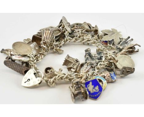 A silver charm bracelet with thirty-four charms including camel, rickshaw, church, doll, various world flags etc, combined ap