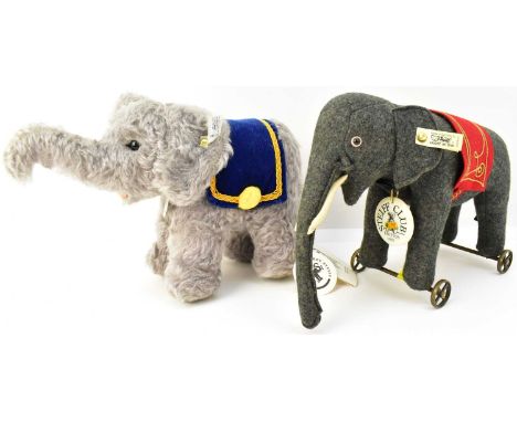 STEIFF; two toy elephants, one grey with raised trunk and blue saddle, button in the ear and still with tags, height 21cm, le