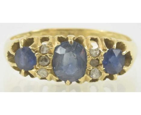 An 18ct gold sapphire and diamond ring, with three graduated claw set sapphires separated by two rows of tiny diamond chips, 