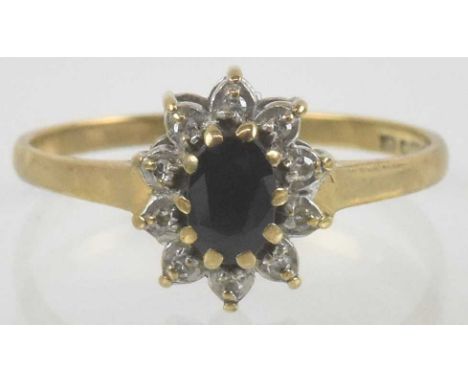 A 9ct gold sapphire and diamond ring, the oval claw set cut sapphire within a flower head of ten tiny claw set diamonds, size