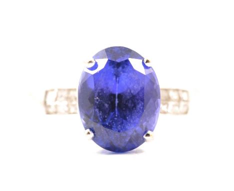 Lorique - a tanzanite and diamond ring, an oval mixed cut tanzanite 12mm x 9.3mm x 7.9mm four claw set, with six princess cut