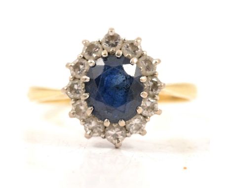 A sapphire and diamond cluster ring, the oval mixed cut sapphire claw set and surrounded by twelve brilliant cut diamonds in 