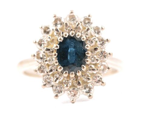 A sapphire and diamond oval cluster ring, the oval mixed cut sapphire claw set and surrounded by a double surround of thirty-