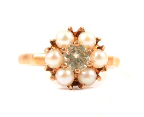 A pearl dress ring, six cultured pearls surrounding a pale untested green stone, claw set in a yellow metal mount ring size M