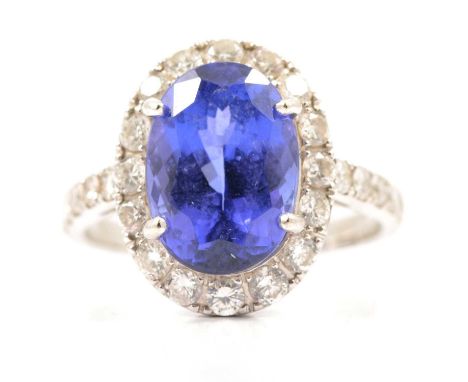 A tanzanite and diamond cluster ring, an oval mixed cut violet blue tanzanite 11.7mm x 8.3mm x 6mm, four claw set and surroun