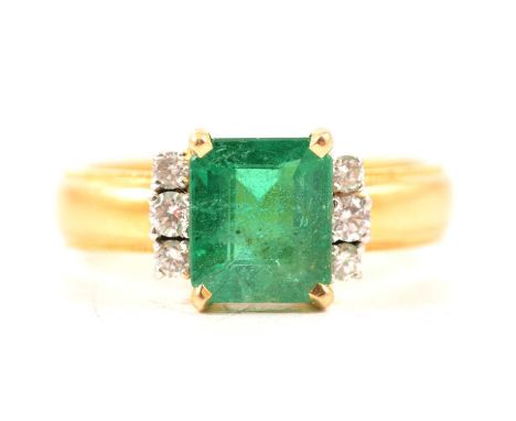 An emerald and diamond ring, the emerald cut emerald claw set with three brilliant cut diamonds to each side in a yellow and 