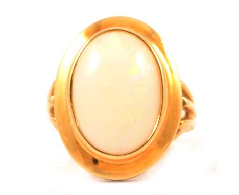 An opal dress ring, the oval cabochon cut stone 17.5x12mm collet set in an 18 carat yellow gold mount ring size approximately