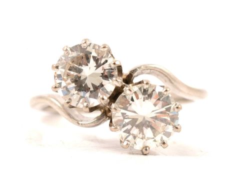 A diamond two stone crossover ring, the brilliant cut stones claw set in an all white metal mount ring size O, total weight o