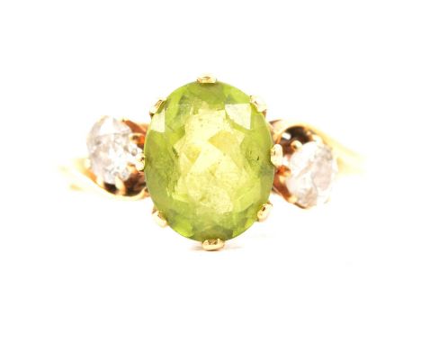 A peridot and diamond three stone ring, the oval mixed cut peridot approx. 9.5mm x 8.2mm, claw set in a crossover design with