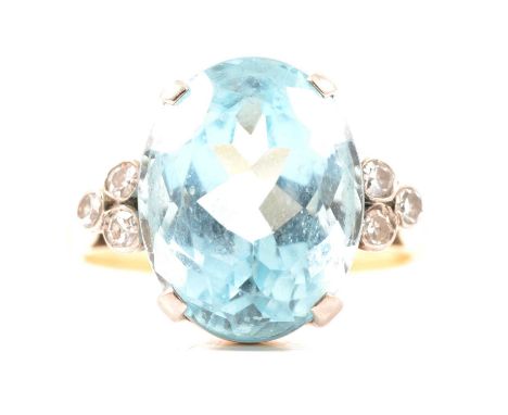 An aquamarine and diamond ring, the oval mixed cut aquamarine 14.5mm x 11.5mm x 7.9mm, four claw set with three bezel set dia