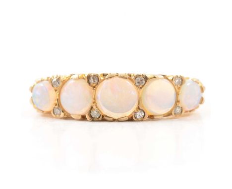 An opal half hoop ring, five round cabochon cut opals graduating in size, claw set and spaced by four pairs of diamonds in a 