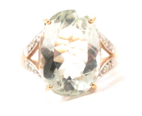 A prasiolite quartz and white stone ring, the oval mixed cut prasiolite quartz 17.9mm x 13.2mm, four claw set with six small 