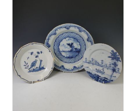 A 19thC Delftware Plate, depicting three figures in river landscape on a boat, D 22cm, together with another Delft Plate, dep