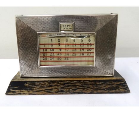 GEORGE V SILVER MOUNTED DESK CALENDARwith engine turned decoration, Birmingham 1934, 8.7cm high x 13.4cm wide, raised on a wo