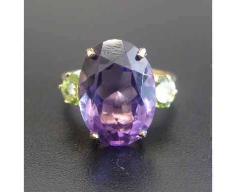 AMETHYST AND PERIDOT THREE STONE RINGthe large central oval cut amethyst approximately 5cts flanked by round cut peridots, on