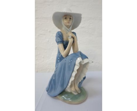 'NAO/LLADRO' FEMALE FIGUREwearing a wide brimmed hat and sitting a on a stone wall, printed and incised marks to base, 27.5cm