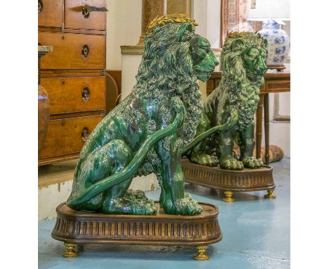 LIONS, a pair, green ceramic, each with a brass laurel wreath on an oval platform base, 100cm H. (2)