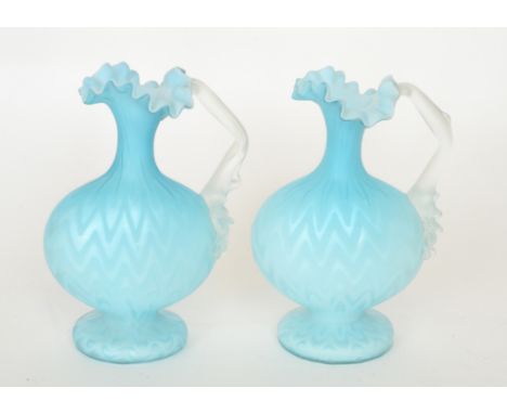 A pair of late 19th Century Stourbridge quilted air trap satin glass ewers of footed compressed ovoid form with collar neck, 