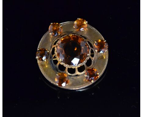 A Victorian yellow metal and citrine circular kilt pin, centred by a circular citrine set within raised and pierced foliate m