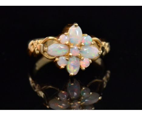 A 9ct hallmarked opal nine stone cluster ring modelled as a flower head to split shoulders, ring size L/E O. 