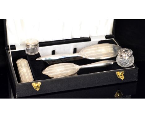 A later 20th Century hallmarked silver four piece dressing table set with engine turned and engraved foliate decoration withi