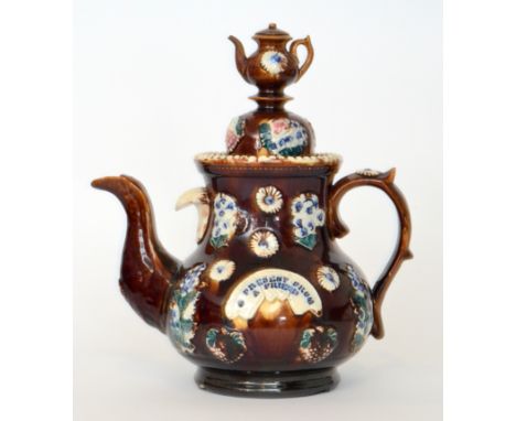 A late 19th Century Barge Ware teapot entitled 'A present from a friend', the typical brown glazed body decorated with low re