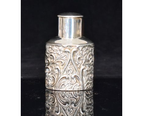 A George V hallmarked silver tea caddy of compressed ovoid form with embossed foliate and C scroll decoration, plain pull off