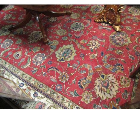 A large Persian tapestry wool rug, red ground with cream and green foliate borders, 370cm x 282cm