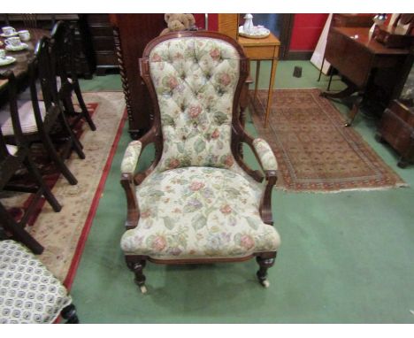 A mid-Victorian carved walnut armchair the button back rest over turned and reeded legs on white ceramic castors