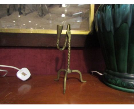 A brass rush light with nips on a tripod base, 22cm tall