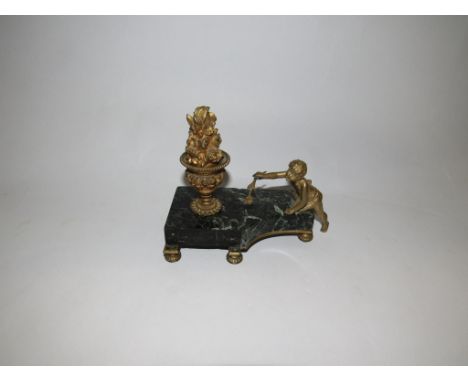 A black marble and gilt ormolu candlestick as putti with flower on footed base, 15cm tall