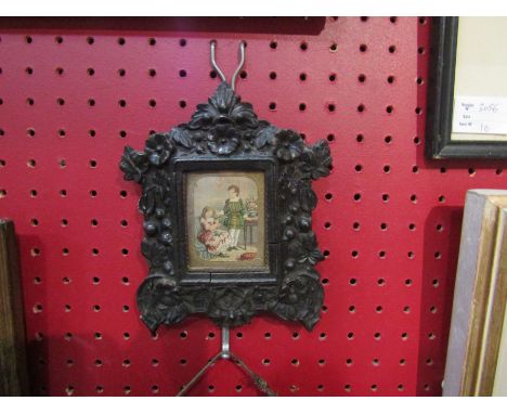 A Victorian coloured print depicting a boy and girl making a garland, framed by gilt paper and housed in an elaborately carve