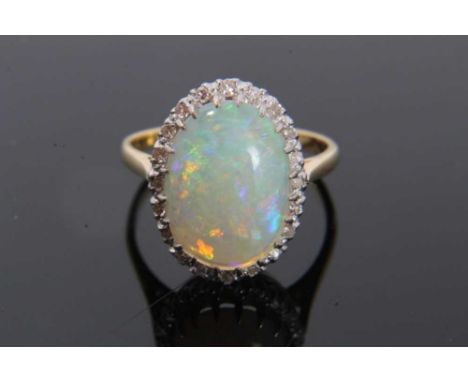 Opal and diamond cluster ring with an oval cabochon opal measuring approximately 14mm x 10.5mm surrounded by 20 single cut di