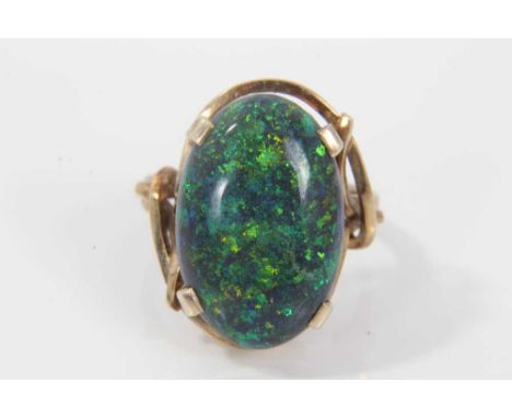 Black opal single stone ring with an oval black opal cabochon measuring approximately 20mm x 13mm x 4.2mm in a 9ct gold setti